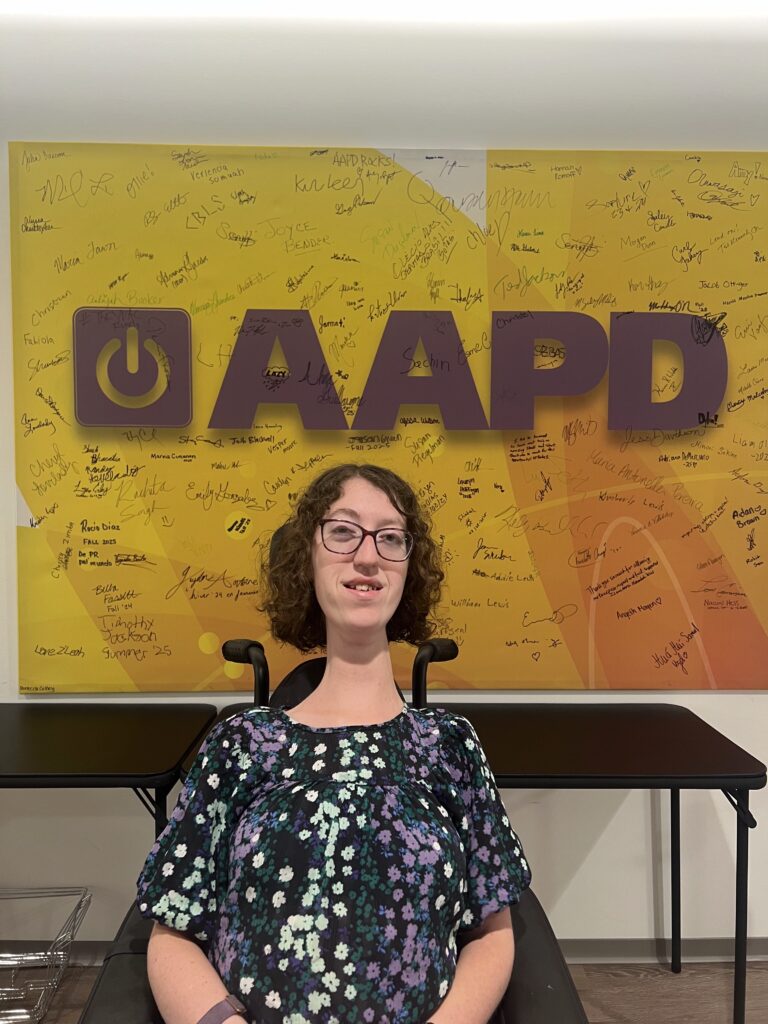 Photo of Naomi Hess in front of the AAPD sign