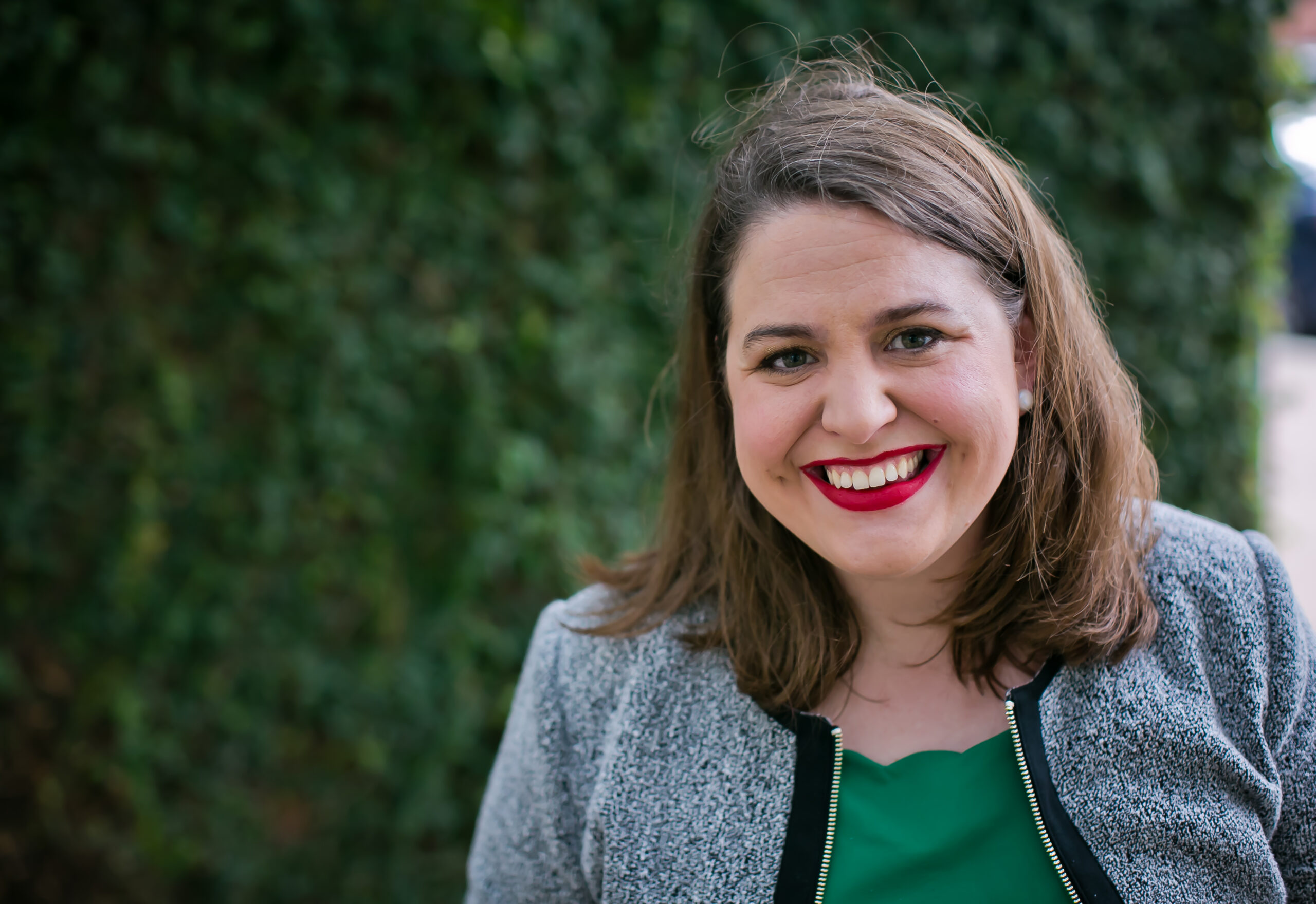 AAPD President and CEO smiles wearing red lipstick and a green blouse