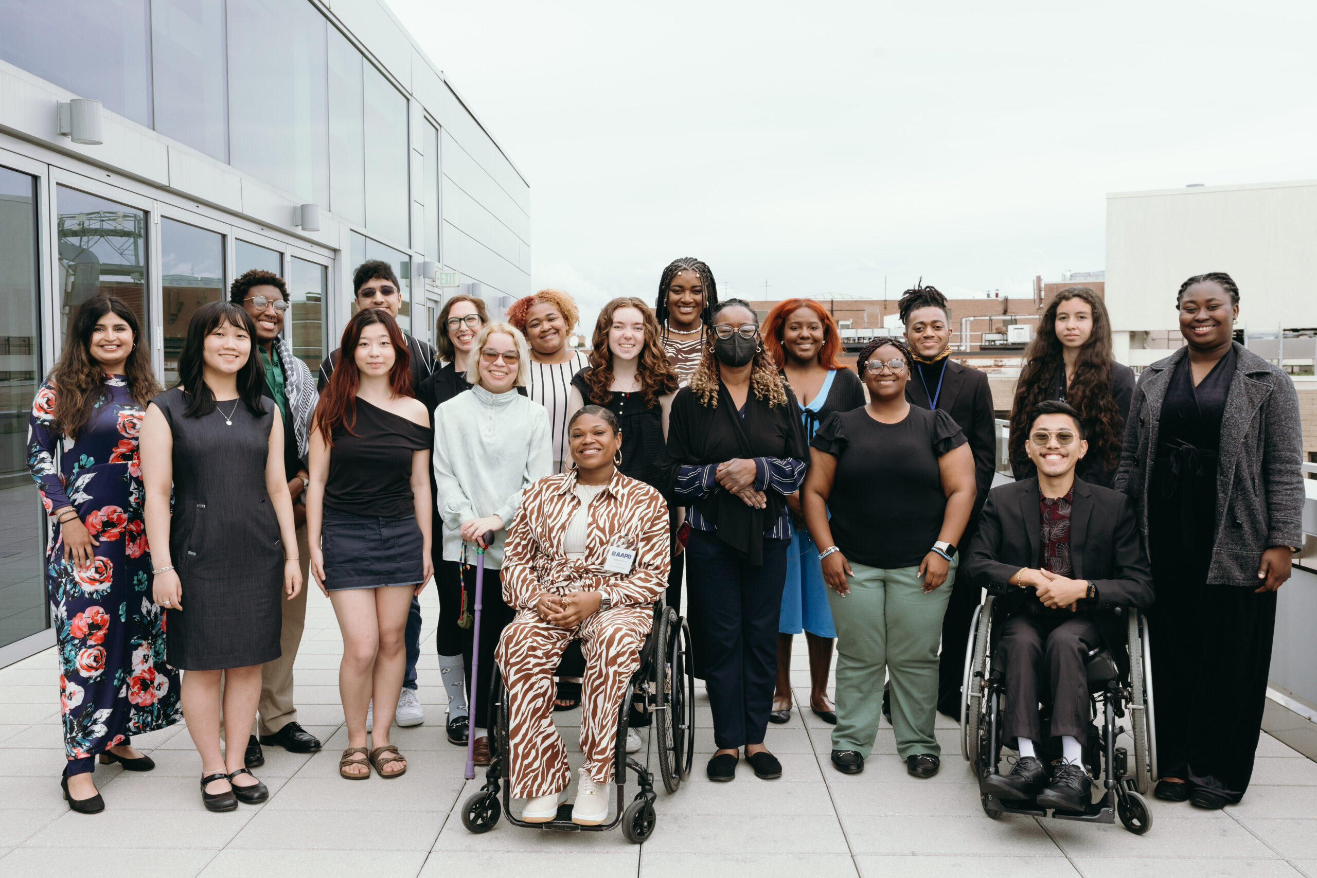 A group of AAPD interns and staff are gathered outside.The group is a diversity of races, genders and disabilities.